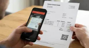 Person scannt einen GiroCode auf einer Papierrechnung mit der Banking-App des Smartphones